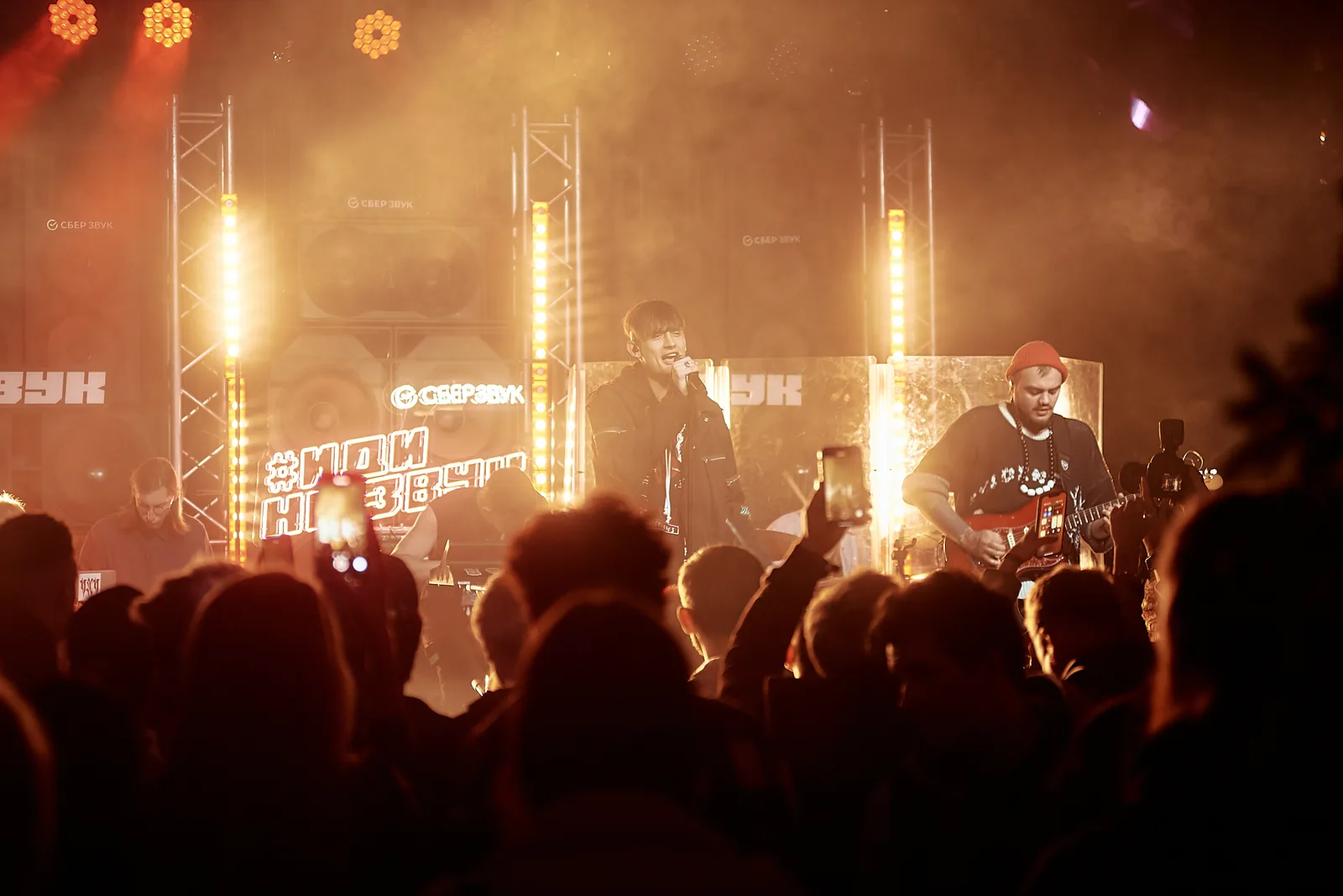 Crowd silhouettes in front of a concert stage with flares